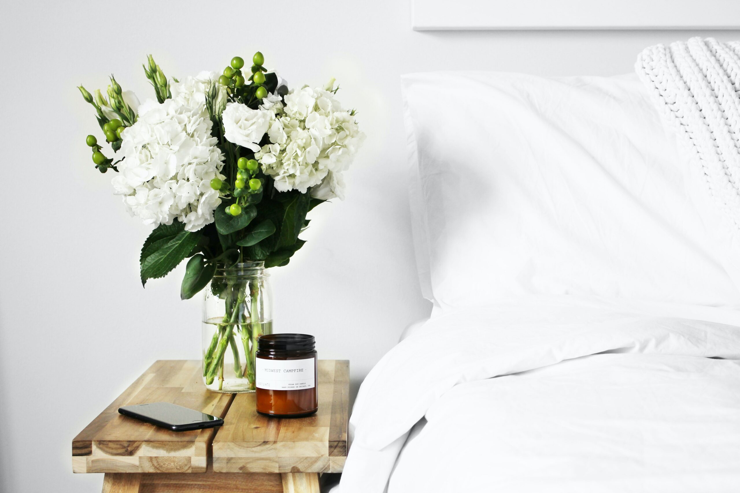 bed and side table with plant Photo by Logan Nolin on Unsplash
