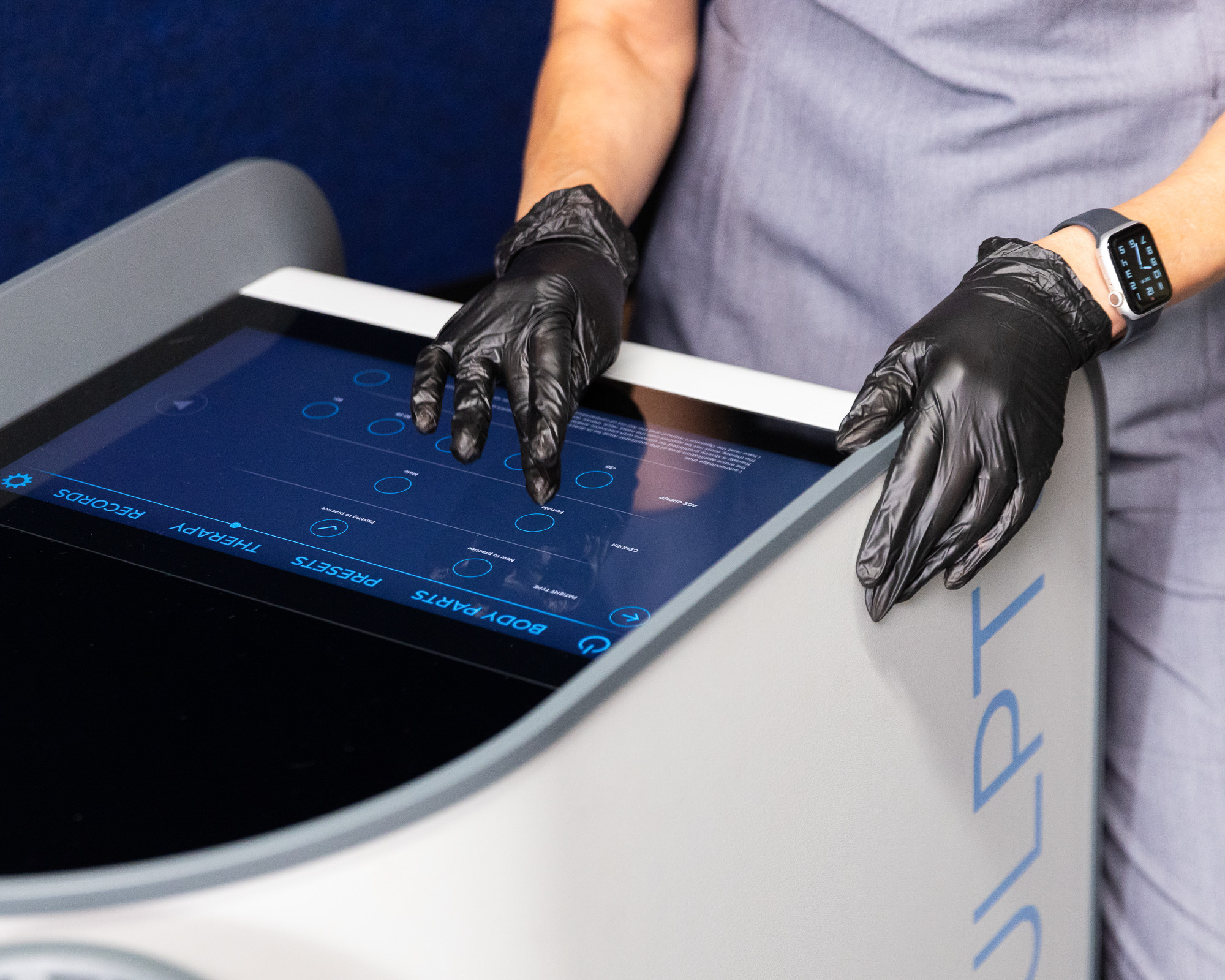 Close up of gloved hands operating the digital control screen for Emsculpt Neo Near Arlington.