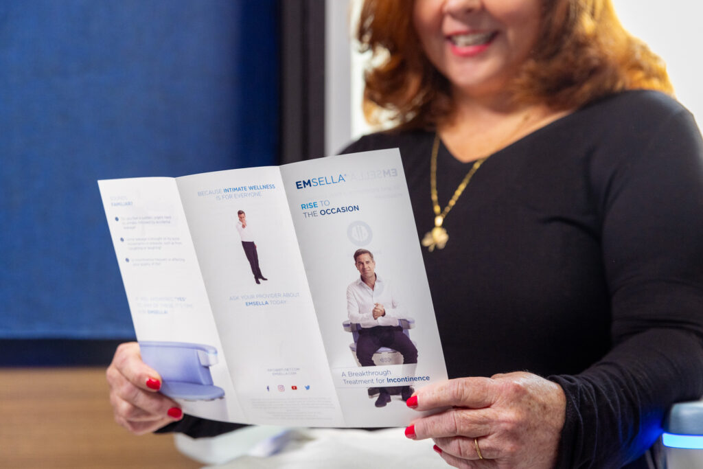 An older woman holding a pamphlet that explains how our Emsella chair works as an option for Overactive Urinary Bladder Treatment in Arlington, VA.