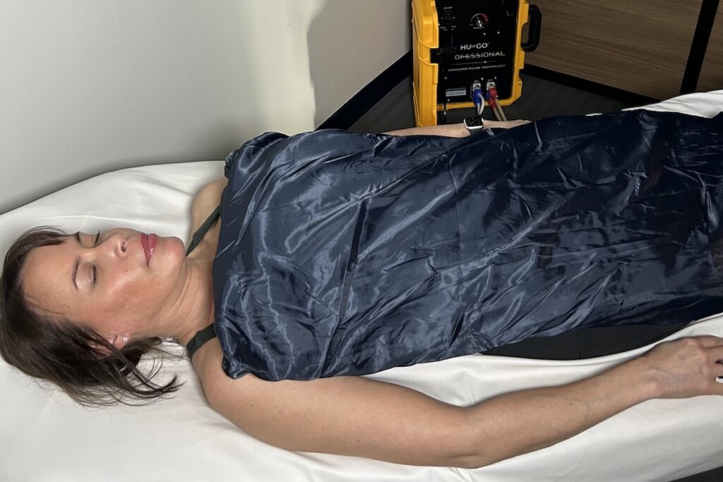 A woman lies down and uses PEMF therapy at a wellness center in Alexandria.